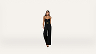 A woman wearing a strapless black jumpsuit with a wide belt and black heels stands against a plain white background.