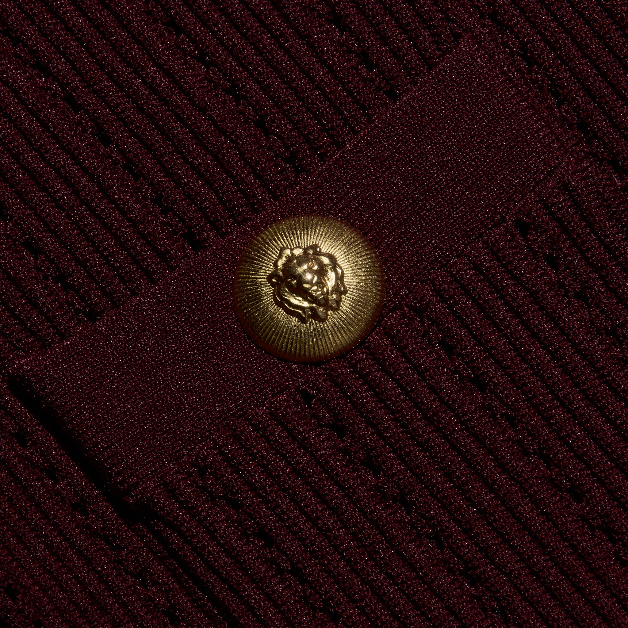 Close-up of the burgundy Irvin Pointelle Knit Cardigan, featuring a round, gold-toned button embossed with a lion head.