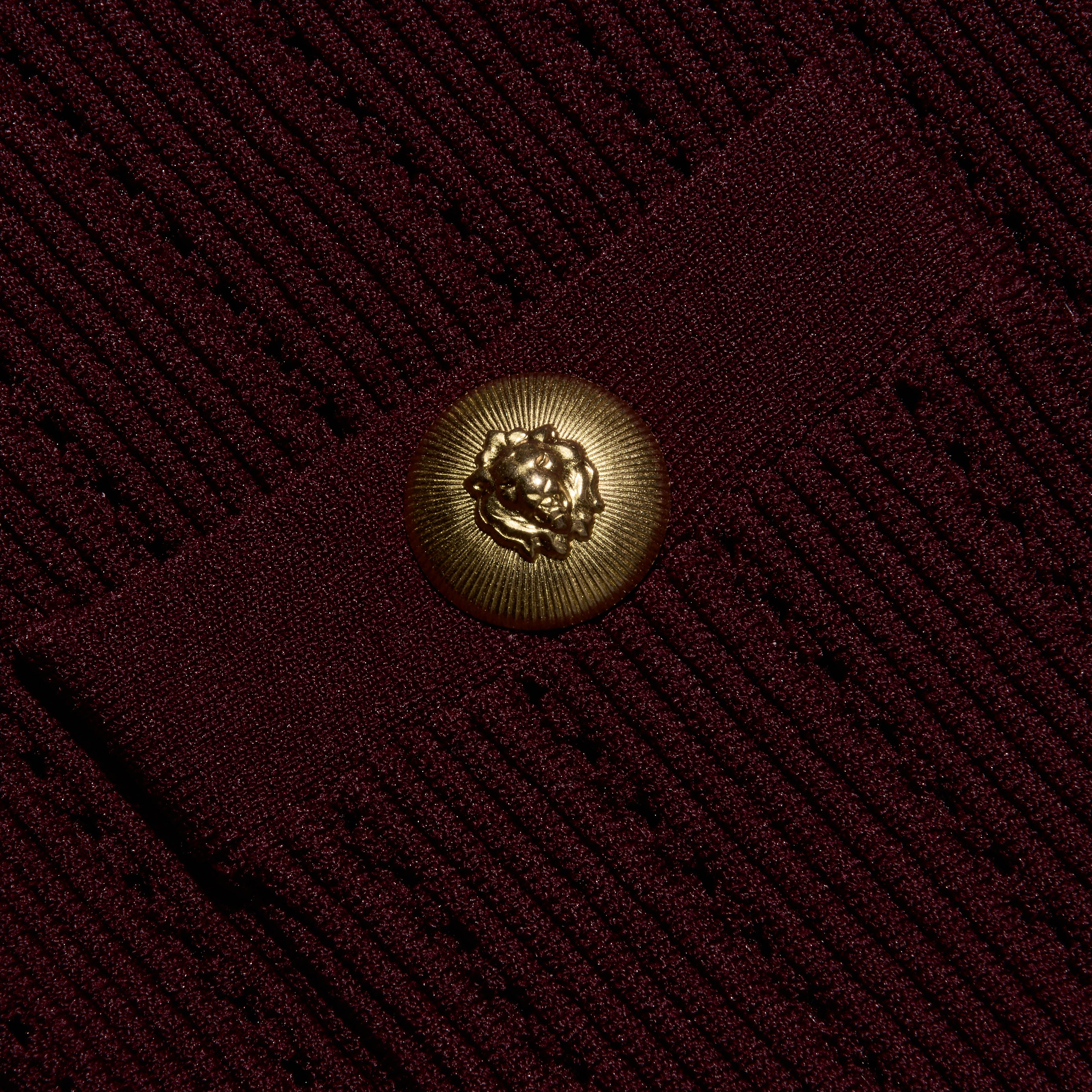 Close-up of the burgundy Irvin Pointelle Knit Cardigan, featuring a round, gold-toned button embossed with a lion head.