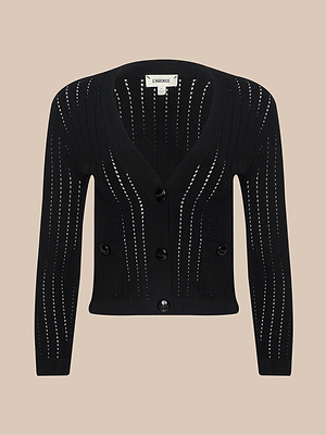 The Irvin Pointelle Knit Cardigan is a black, long-sleeve, button-up sweater with vertical open-knit detailing and two front pockets, shown against a neutral beige background.