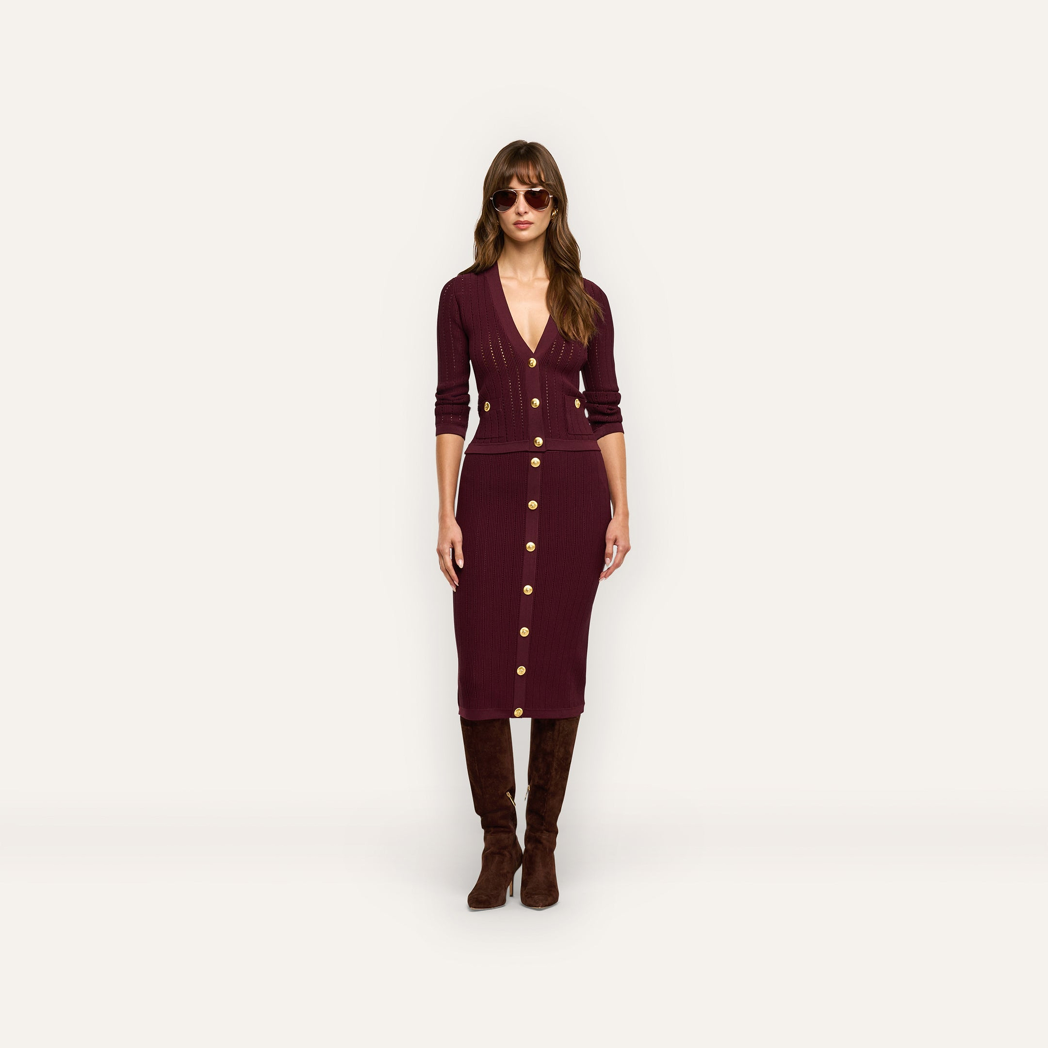 A person wearing a burgundy Melania Pointelle Knit Skirt with a matching cardigan, dark sunglasses, and knee-high boots.