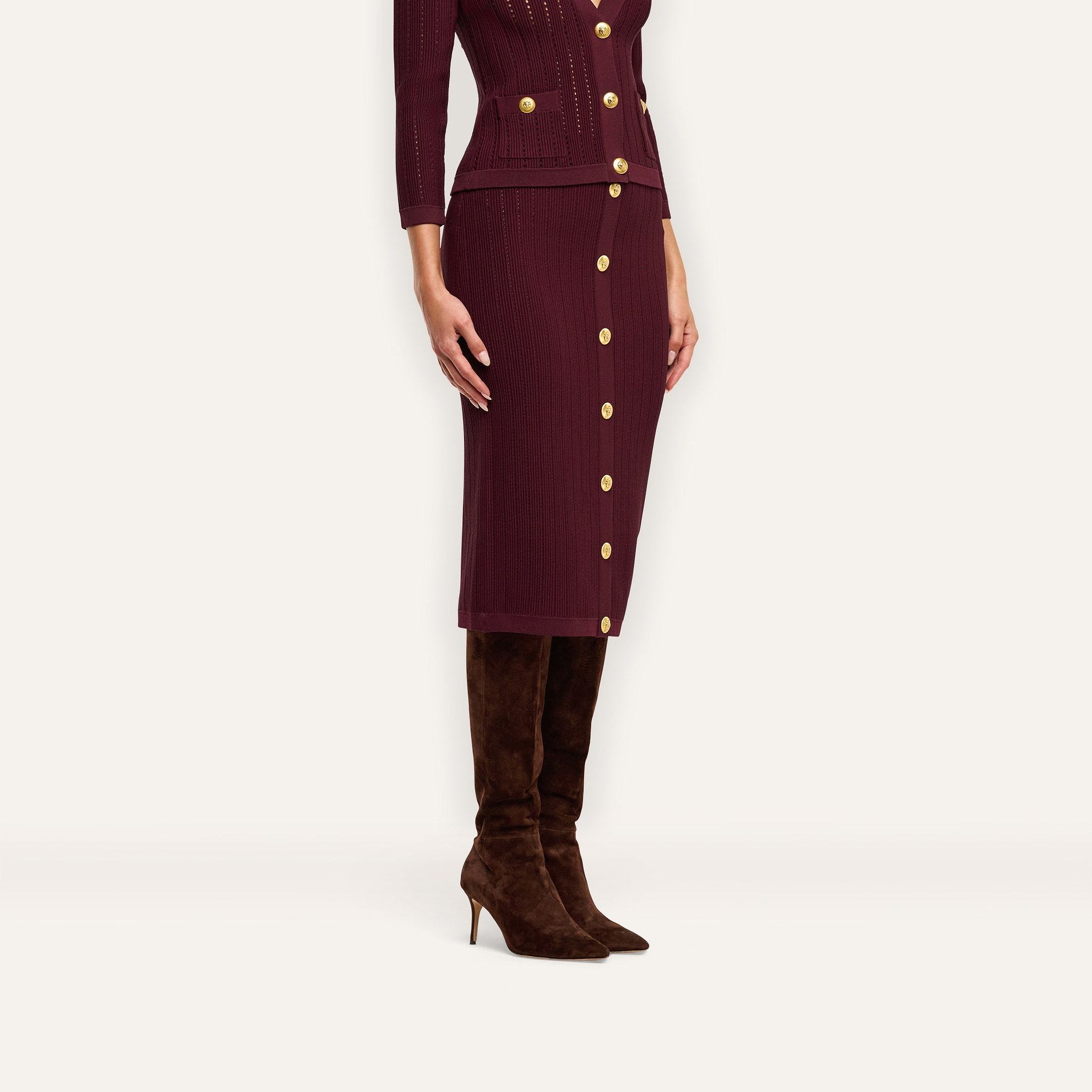 A burgundy Melania Pointelle Knit Skirt in a midi length with an elastic waistband and a front row of gold buttons, worn with a matching button-front cardigan and brown suede knee-high boots.