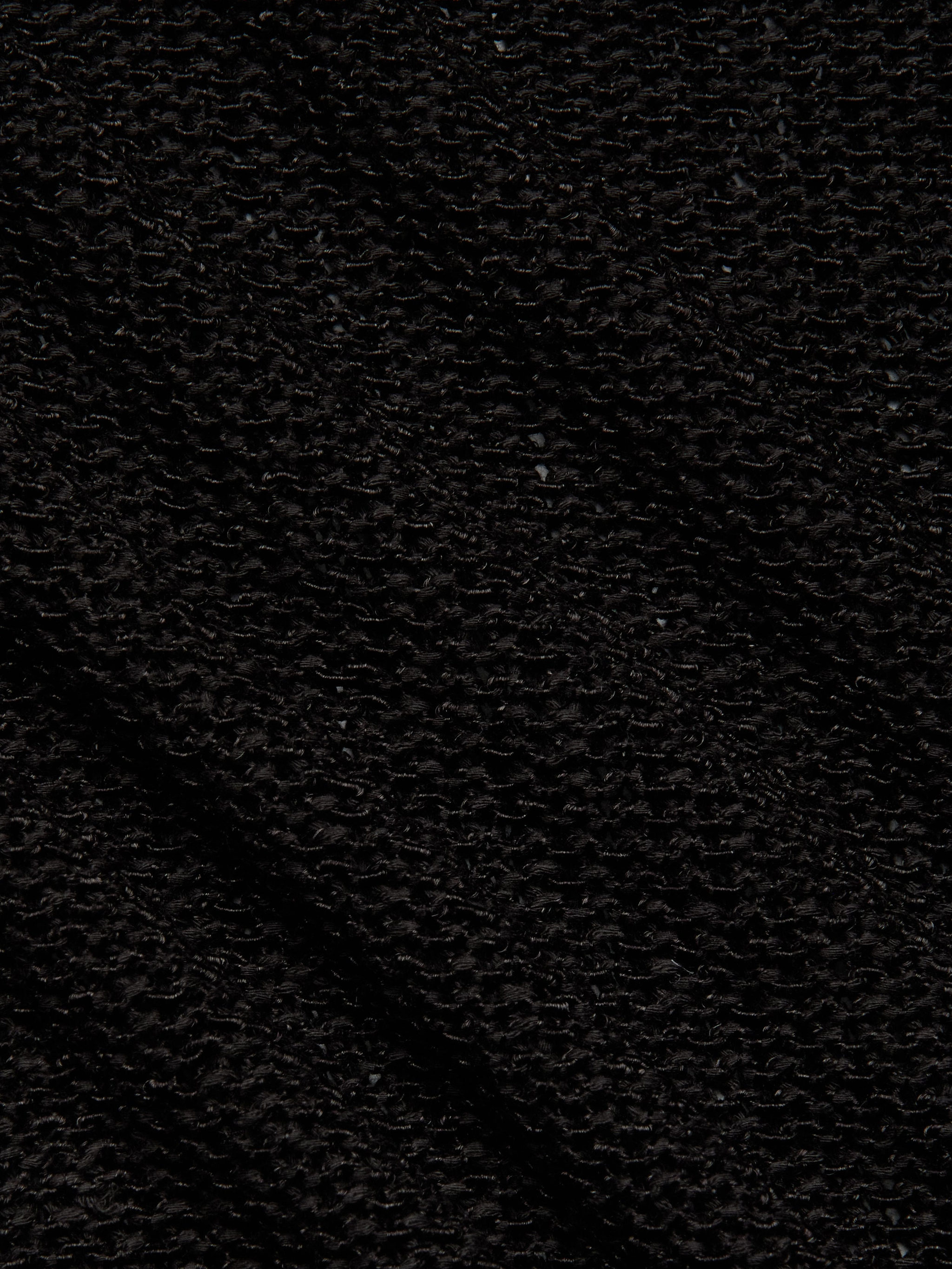 Close-up of Ethan Knit Pullovers black knit fabric, featuring a waffle-like grid pattern. The surface looks soft and textured, with visible shadows highlighting its relaxed fit and intricate design.