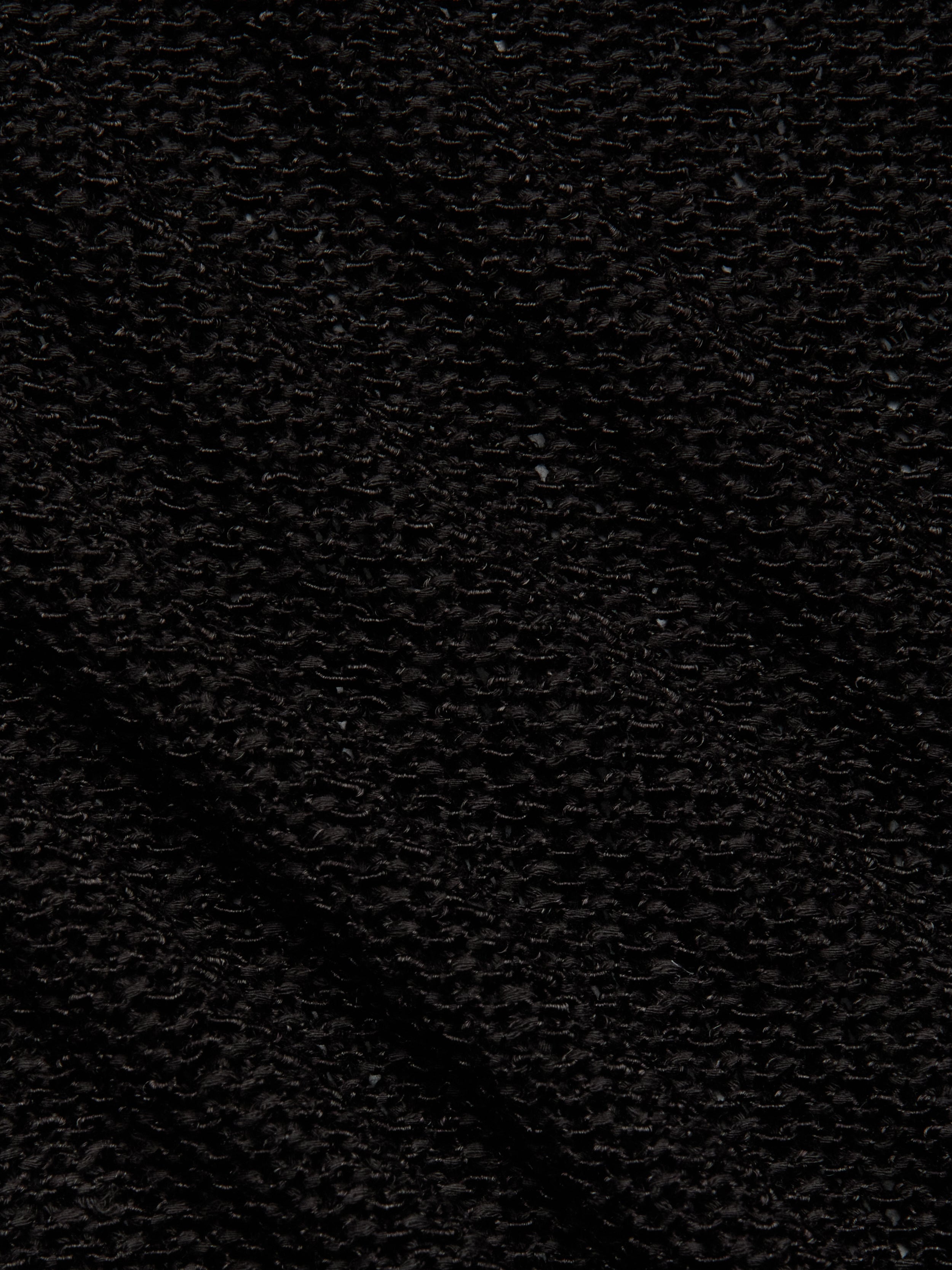 Close-up of Ethan Knit Pullovers black knit fabric, featuring a waffle-like grid pattern. The surface looks soft and textured, with visible shadows highlighting its relaxed fit and intricate design.