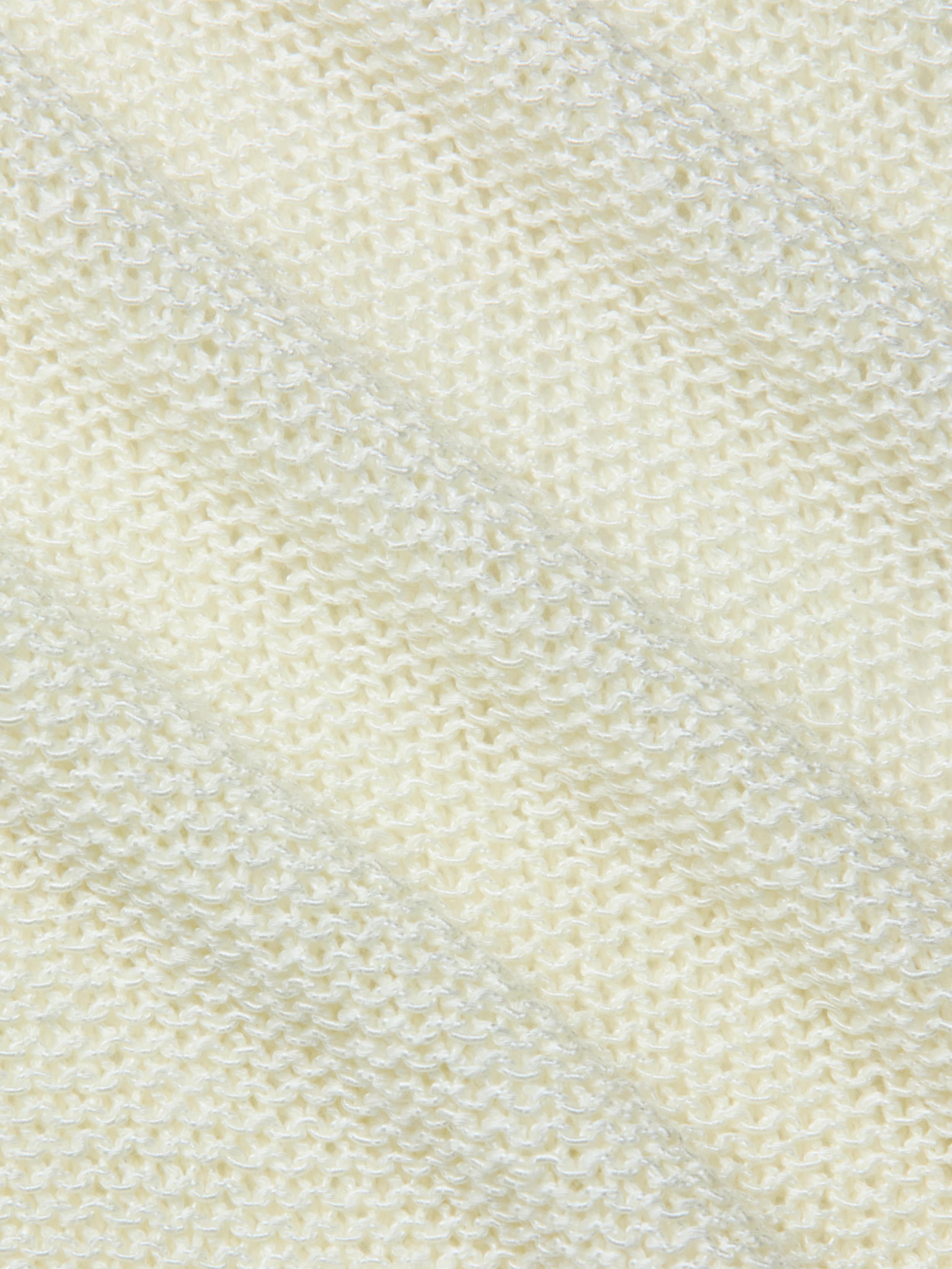 Close-up of the textured, cream-colored fabric of the Ethan Knit Pullover, featuring a diagonal ribbed pattern that highlights the fine stitches and softness of this knit garment.