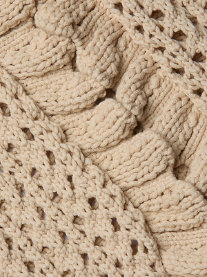 Close-up of the Solaris Crocheted Cardigan’s beige knit, displaying open-stitch patterns, woven cables, and lacy details for a textured, cozy look—perfect as a lightweight layering piece.