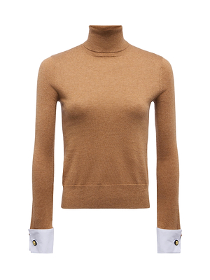 The Flora Turtleneck by L'AGENCE is a camel-colored sweater with long sleeves, contrasting white French cuffs each accented by a black button, showcased against a plain white background.