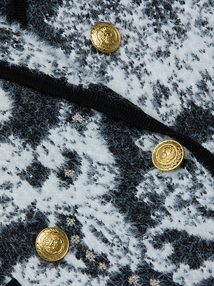 Close-up of the L'AGENCE Eileen Jacquard Knit Blazer, featuring a textured black and white pattern and three shiny gold embossed buttons.
