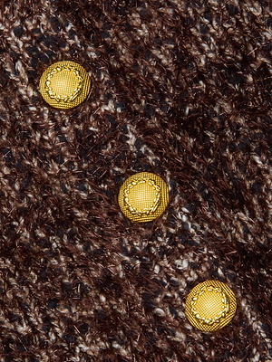 Close-up of the Una Knit Cardigan’s textured brown and beige knit fabric, highlighted by three shiny yellow buttons arranged diagonally.