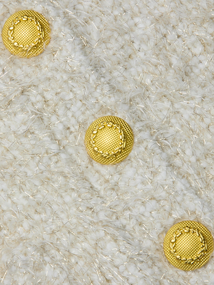 Three ornate gold buttons on textured white and beige woven fabric with metallic threads add elegant detail to the tailored Una Knit Cardigan.