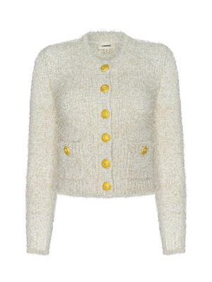The Una Knit Cardigan is cream-colored with a textured eyelash knit, long sleeves, two front pockets, and six large gold buttons down the center.