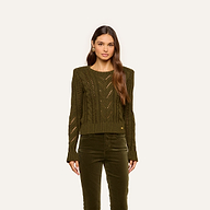 A woman with long brown hair wears the Mio Cabled Pullover in olive green and matching olive green pants, standing against a plain light background, facing forward with a neutral expression.