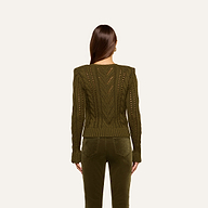 A woman with long brown hair, seen from behind, wears the Mio Cabled Pullover—a cotton-blend olive green crewneck sweater with a cabled knit—paired with matching green pants against a plain light background.