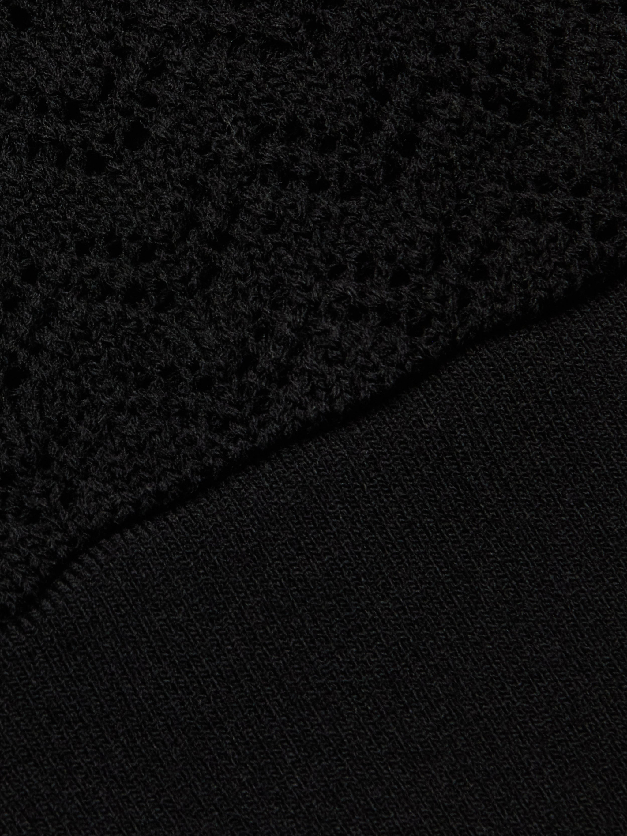 Close-up of two black fabrics: the upper half showcases the Reverie Pointelle Knit Bralette with its textured, openwork pointelle knit, while the lower half displays a smooth, tightly knit material.