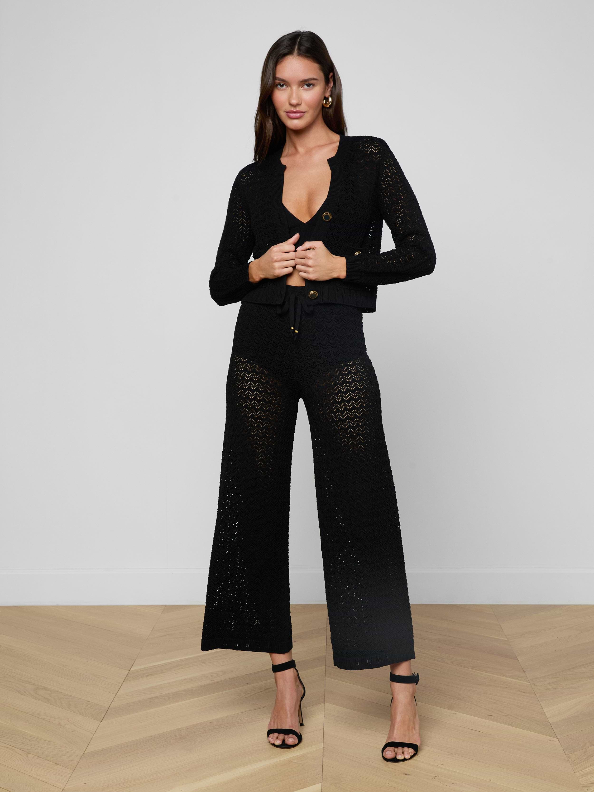 A woman stands against a plain light background wearing the Orla Pointelle Knit Cardigan paired with matching wide-leg pants and black high-heeled sandals.