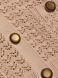 Close-up of the Orla Pointelle Knit Cardigan, featuring textured beige fabric with an intricate lace-like pointelle knit pattern and two round gold buttons with decorative edges.