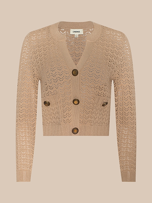 The Orla Pointelle Knit Cardigan is a beige, cropped long-sleeve layer featuring chevron lace knit, front pockets, and three large brown buttons—a stylish choice for breezy days.