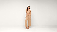 Woman stands in a neutral studio wearing a beige crop top and wide-leg crochet pants, paired with sandals. She looks forward with a relaxed posture.