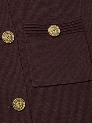 Close-up of the Isabel Knit Coat, a brown double-breasted design with a patch pocket, three embossed gold crest buttons, and decorative horizontal stitching on the pocket.