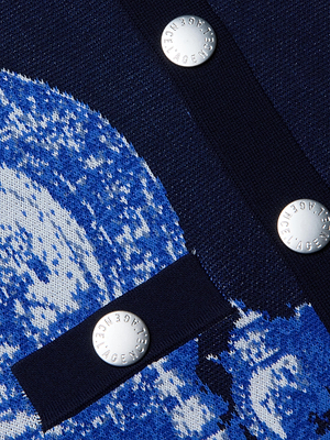 Close-up of the Osiris Jacquard Cardigan by L'AGENCE, featuring blue and white motif fabric with three metallic, logo-engraved buttons arranged on a navy strip for refined detail.