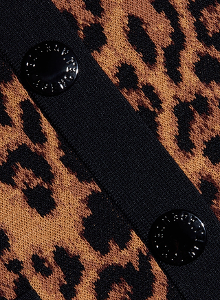 Close-up of the Osiris Jacquard Cardigan, showcasing its leopard print jacquard knit fabric with two black, round buttons sewn onto a black strip that runs diagonally across the patterned material.