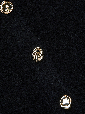 Close-up of the Melissa Knit Cardigan by L'AGENCE in black, featuring three shiny gold buttons with organic designs. The buttons are aligned vertically along a seam, creating a sophisticated contrast against the textured knit fabric.