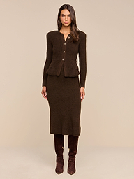 A woman stands facing forward against a plain beige background, wearing the Melissa Knit Cardigan in brown paired with a matching mid-length skirt and dark brown knee-high boots.