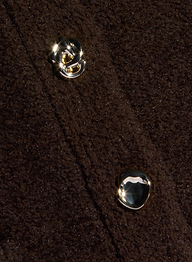Close-up of a dark brown textured yarn fabric with two shiny, gold-toned buttons. The fabric appears thick, possibly wool or fleece, and the buttons have unique, irregular shapes—perfect for a stylish piece of women’s knitwear like the Melissa Knit Cardigan.