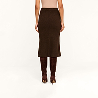 A person wearing the Salem Knit Skirt in brown, paired with brown suede knee-high boots, is standing against a beige background. The image captures the back view from shoulders to feet.