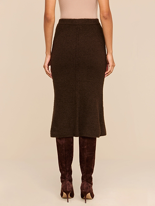 A person wearing the Salem Knit Skirt in brown, paired with brown suede knee-high boots, is standing against a beige background. The image captures the back view from shoulders to feet.