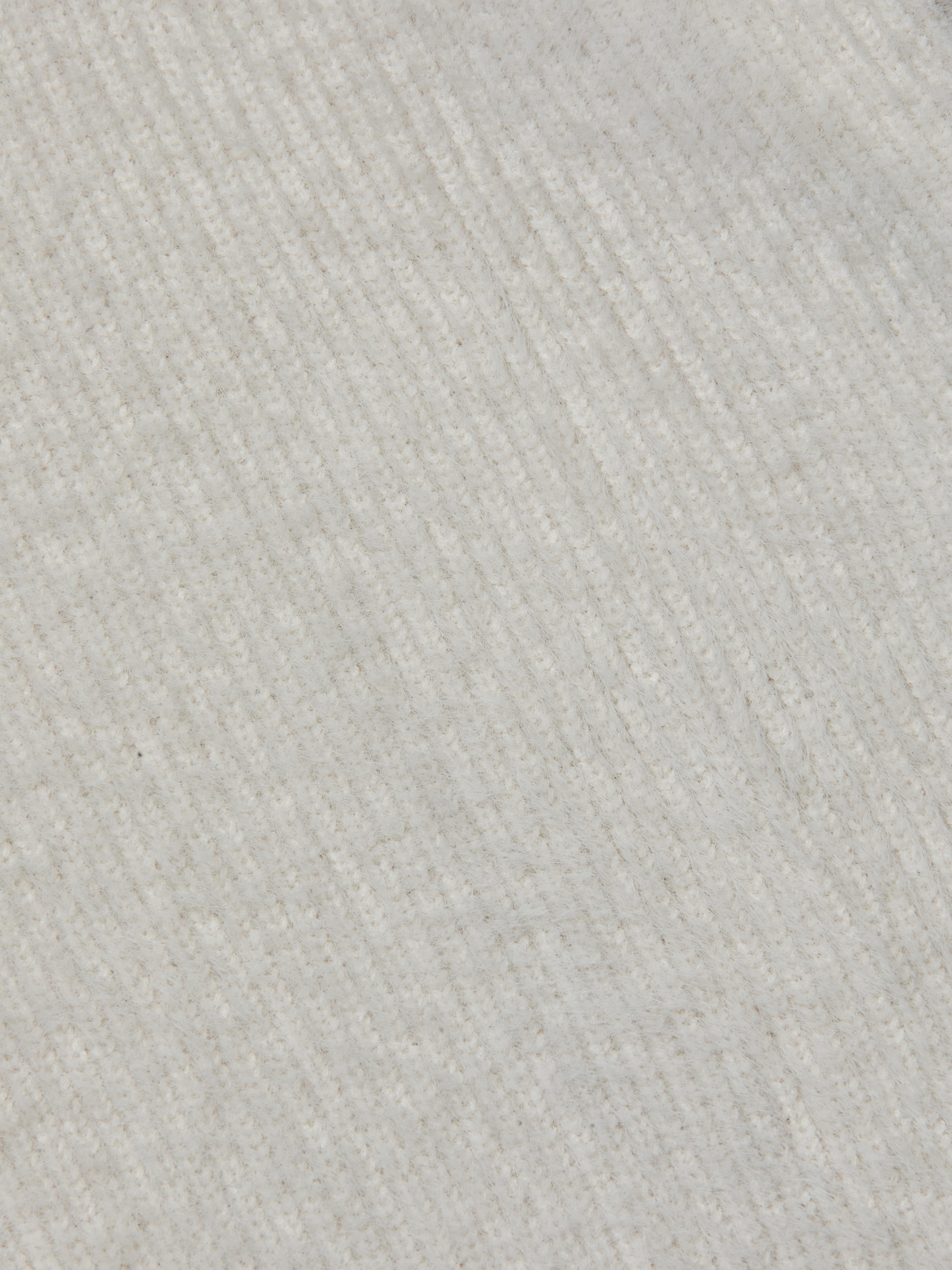 Close-up of the Guinevere Cropped Pullover’s ultra soft knit fabric, featuring diagonal ribbed lines that create a subtle pattern across the surface. The material appears cozy and plush.