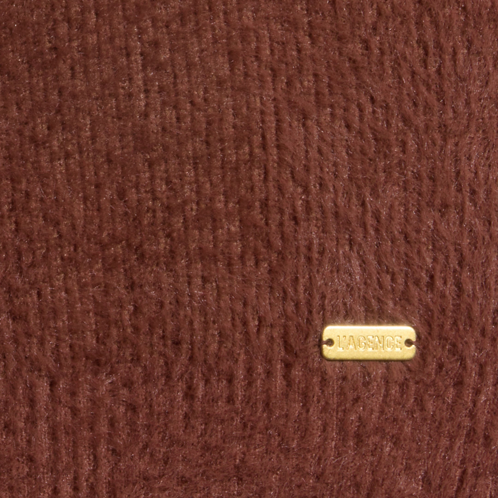 Close-up of the Guinevere Cropped Pullover, featuring ultra-soft brown knit fabric and a small rectangular gold tag in the bottom right corner displaying the brand name LAGENCE.
