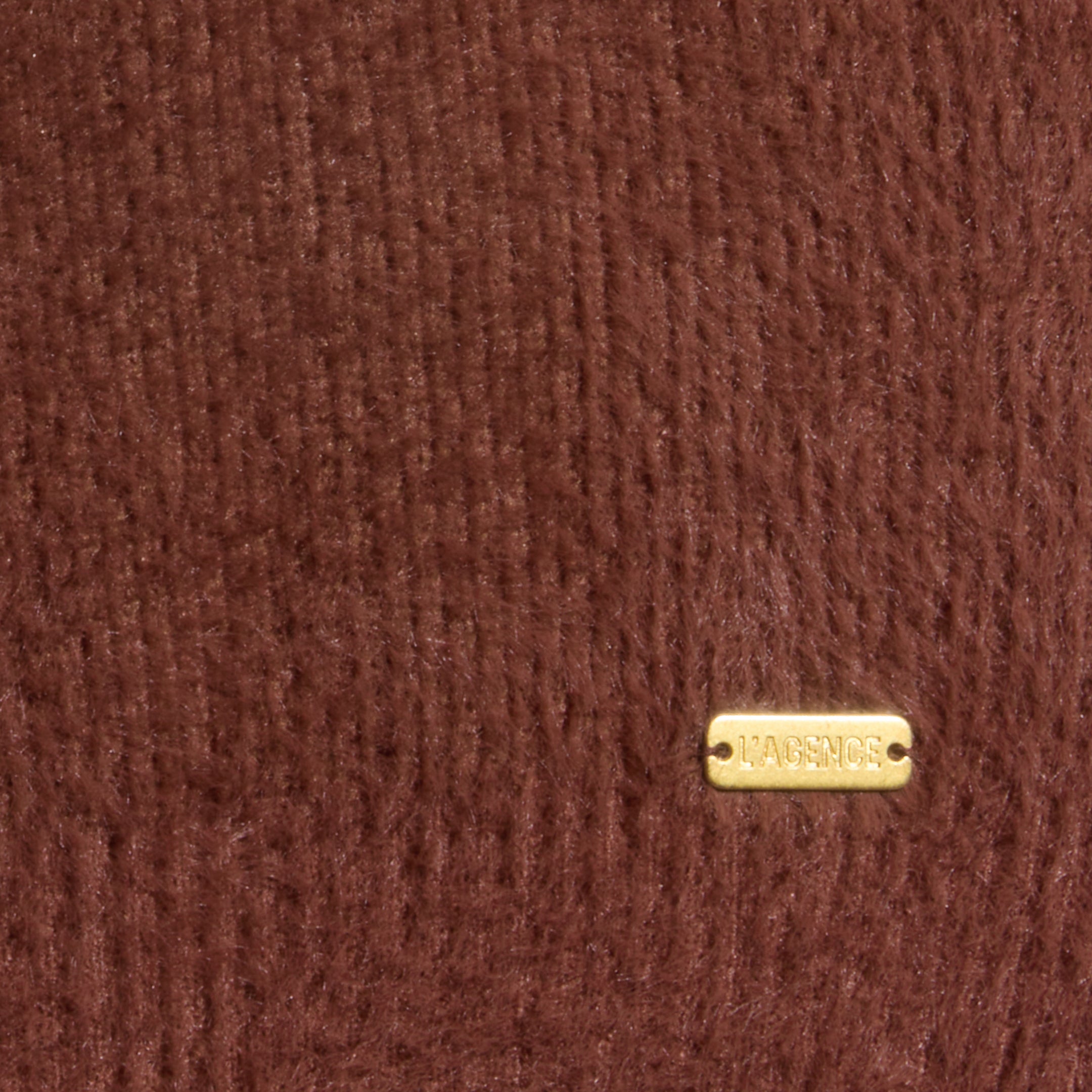 Close-up of the Guinevere Cropped Pullover, featuring ultra-soft brown knit fabric and a small rectangular gold tag in the bottom right corner displaying the brand name LAGENCE.