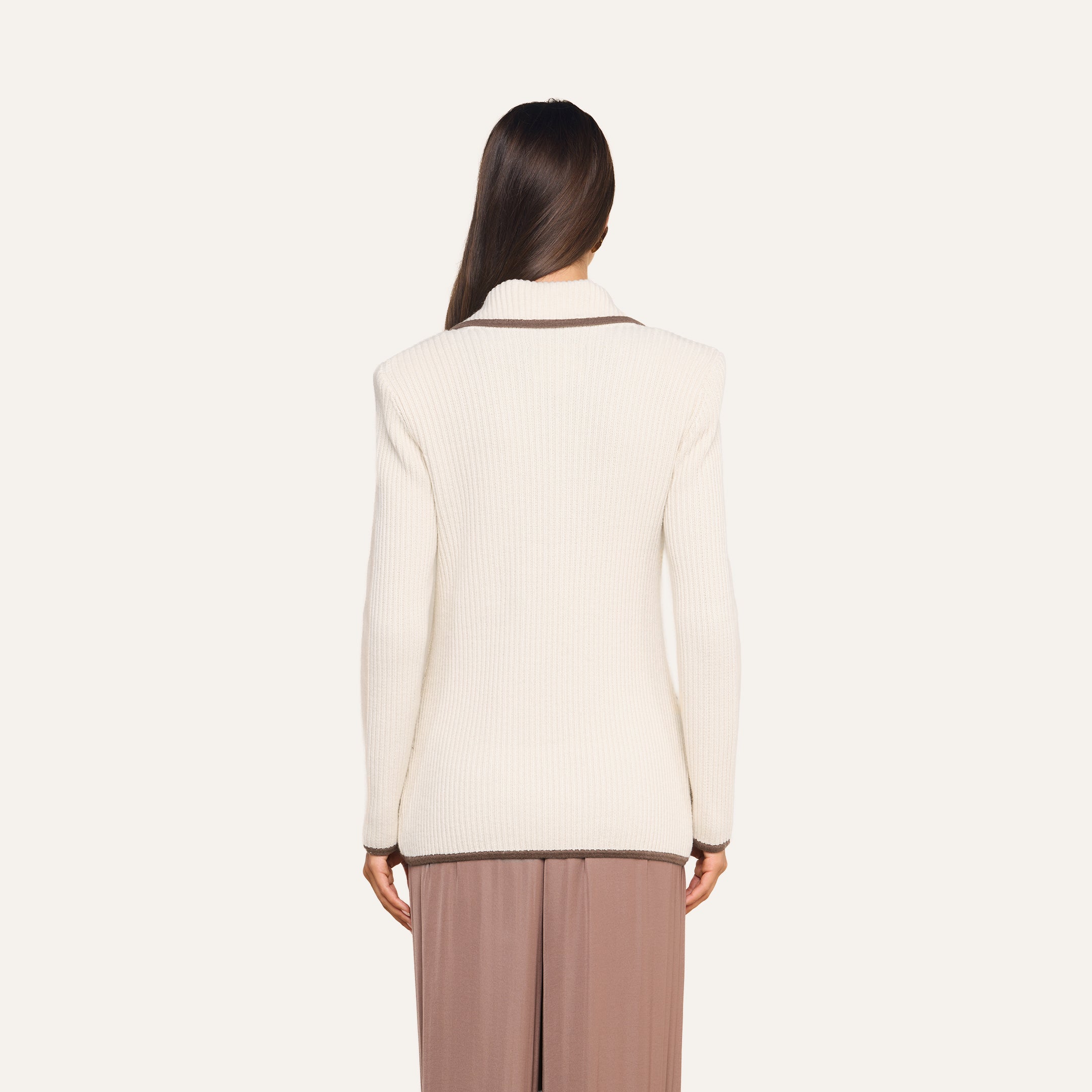 A woman with long brown hair is shown from the back, wearing the cream-colored Ranch Knit Blazer with a collar and taupe wide-leg pants against a plain light background.