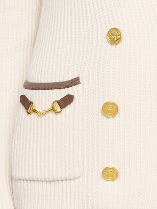 Close-up of the Ranch Knit Blazer in cream, showcasing its ribbed knit design, gold buttons, a pocket outlined in brown, and a decorative brown leather and gold hardware accent on the pocket.