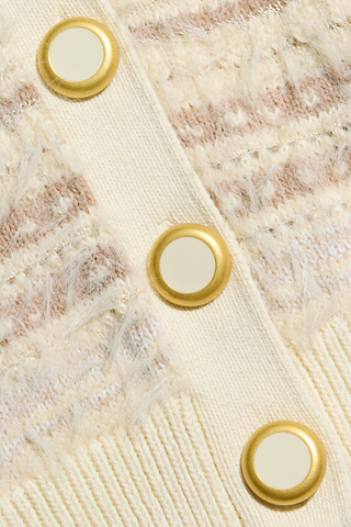 Close-up of the Ariadne Cardigan, a cream-colored cotton-blend textured sweater featuring gold-rimmed white buttons arranged in a vertical line.