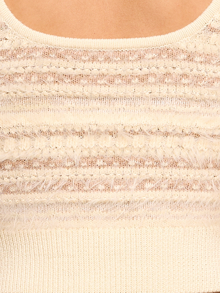 Close-up of the Galene Tank, a cropped knit tank in an ecru colorway, featuring cream-colored textured knit fabric with horizontal stripes and a ribbed hem, with part of a scoop neckline visible at the top.