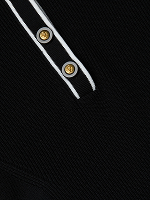 Close-up of the Yaretzi Knit Midi Dress by L'AGENCE Sale, a black ribbed design with white trim and a button placket featuring two gold buttons, blending polo style with a polished, modern look.