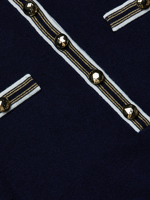 Close-up of the L'AGENCE Malaki Cropped Sweater in navy featherweight knit, with gold-tone and black buttons, plus horizontal white and gold-striped trim resembling pocket flaps and a front seam.
