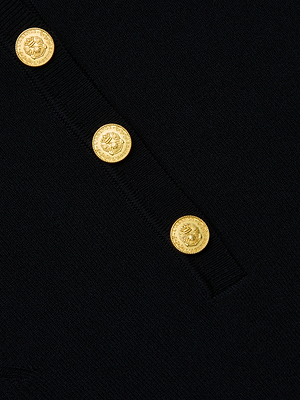 Close-up of the L'AGENCE Elisabetta Knit Bodysuit in black stretch ribbed fabric, featuring four shiny gold embossed buttons arranged diagonally along a seam.