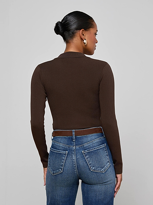 Seen from behind, a woman with her hair in a bun wears the Elisabetta Knit Bodysuit in fitted chocolate brown ribbed knit, paired with blue jeans with back pockets, a brown belt, and gold hoop earrings against a plain light grey background.
