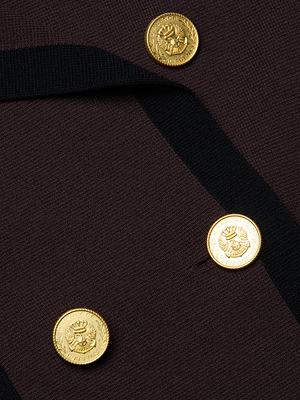 Close-up of three gold embossed crest and laurel buttons on the Janu Cropped Knit Jacket by L'AGENCE, featuring dark brown knit fabric with black trim.