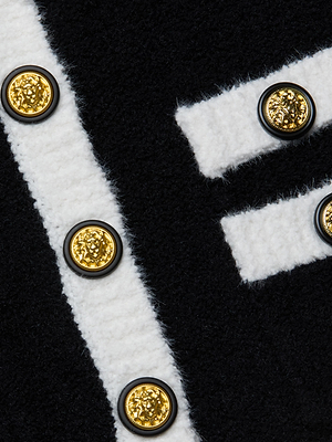 The L'AGENCE Lottie Knit Mini Skirt features black and white vertical and horizontal stripes, finished with embossed gold buttons for a refined, tailored look.