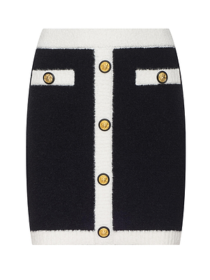 The L’AGENCE Lottie Knit Mini Skirt is black with white trim, features six gold front buttons, and has two decorative top horizontal pockets each finished with a matching gold button.