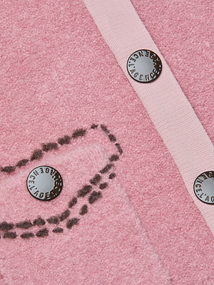 Close-up of the Poetry Cardigan: textured pink bouclé knit, tailored collar, black thread outlining a pocket shape, three black buttons with 