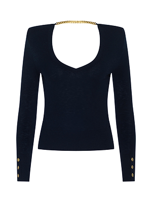 The Kolie Chain Top is a fitted black long-sleeve with structured shoulders, gold buttoned cuffs, a deep scoop neck, and a high-shine chain detail connecting the shoulders at the back.