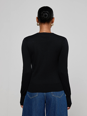 A person with dark hair in a bun and gold hoop earrings models the L'AGENCE Ronda Knit Henley Top in black with lion head buttons and blue wide-leg jeans, shown from the back against a plain light background.