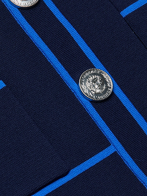 Close-up of the Tala Cardigan in dark blue power knit with bright blue stripes, featuring two metallic round buttons embossed with a classical-inspired face.