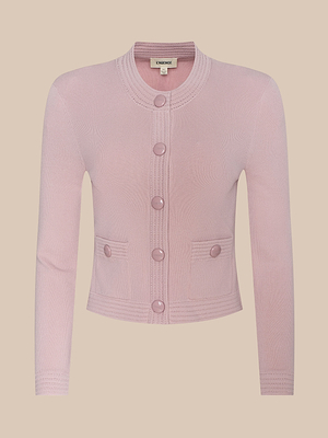 The Patsy Cropped Cardigan is a light pink, long-sleeve, power knit button-up with a round neckline, two front pockets, and matching pink buttons, shown on a plain beige background.
