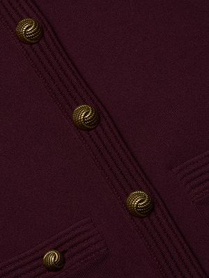 Close-up of the Patsy Cropped Cardigan by L'AGENCE, featuring burgundy power knit fabric, gold signature snap buttons, vertical ribbed trims, and two parallel small pockets at the bottom.